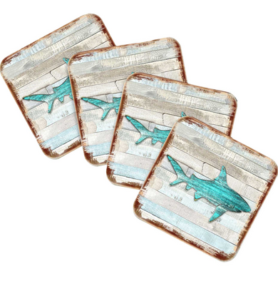 four square coasters with a design of a shark on them.