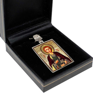 a pendant or religious icon displayed in a black box, which is placed on a white surface.