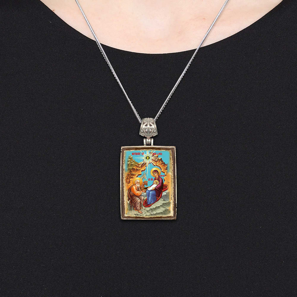 A silver pendant necklace with a religious icon hanging from it.