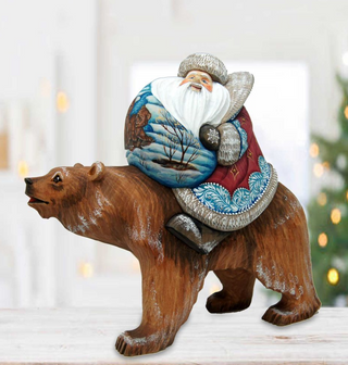 A wooden bear statue of Santa Claus riding on top of a bear.