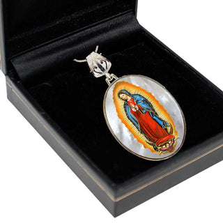 A pendant featuring the image of the Virgin Mary, with a halo and a cross, is displayed in a black jewelry box.