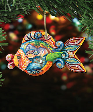 A colorful, handcrafted ornament in the shape of a fish, hanging from a string and surrounded by greenery.