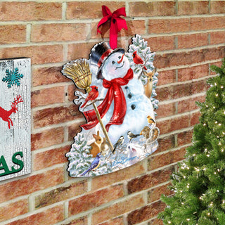 A festive Christmas scene with a snowman, a red bow, and various holiday decorations such as a bird, a rabbit, and a reindeer. The snowman is surrounded by a wreath of snow and pine branches, and the scene is set against a brick wall.