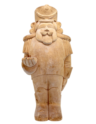 A wooden nutcracker figure with a hat and a bowl in its hand, standing against a black background.