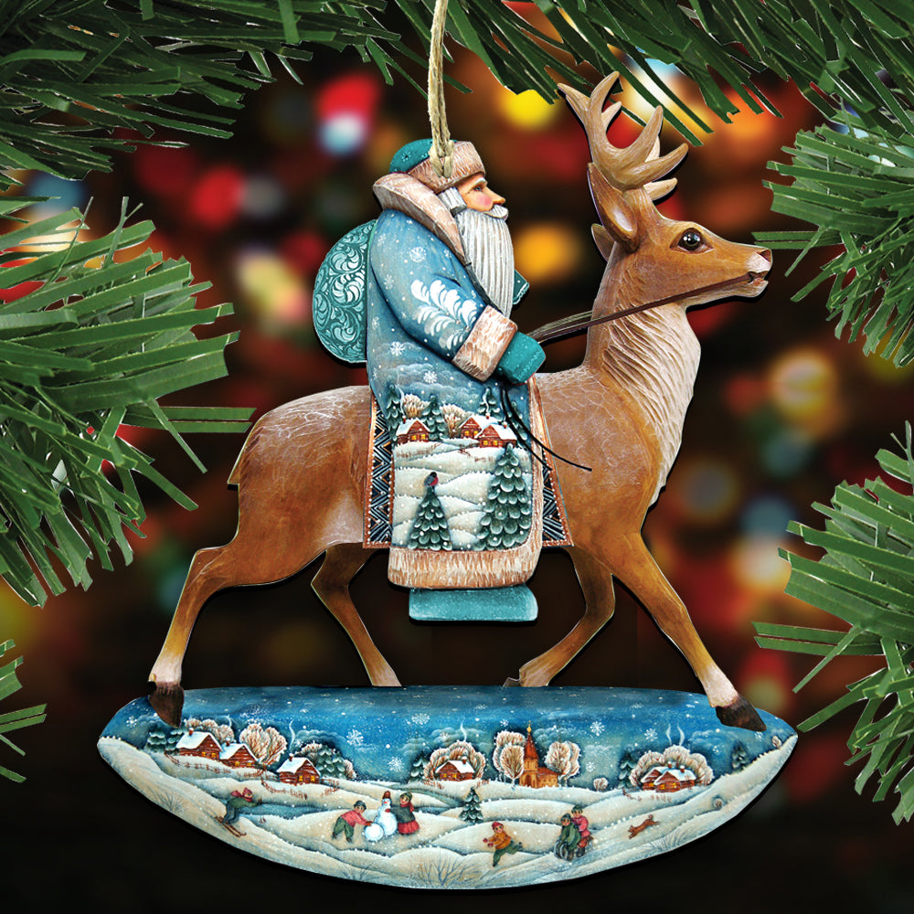 A Christmas ornament depicting Santa Claus riding a reindeer, with a snowy landscape and houses in the background.