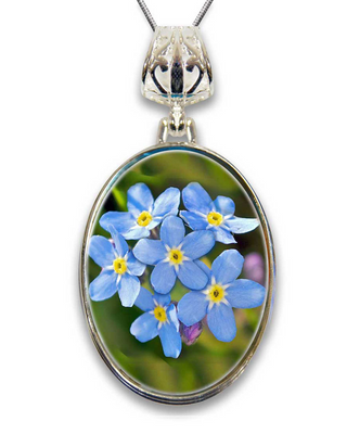 A silver pendant necklace with a circular frame containing a close-up image of blue forget-me-not flowers.