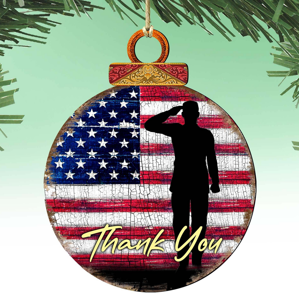 A Christmas ornament with a silhouette of a person saluting in front of an American flag.