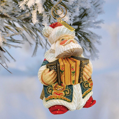 A decorative ornament of Santa Claus holding an accordion is hanging on a tree branch.