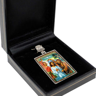 a pendant with a religious scene, including figures of Jesus Christ and other religious figures, displayed in a black jewelry box.