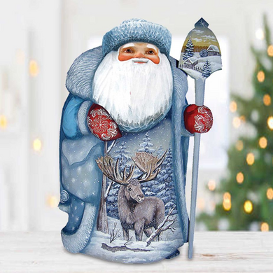 A hand-painted Santa Claus figurine holding a reindeer and a snow globe, set against a snowy winter landscape with a Christmas tree in the background.