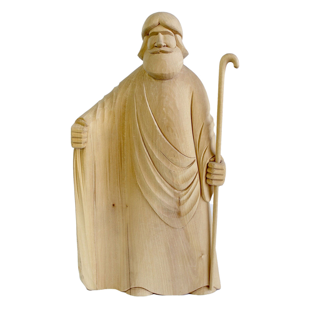 A wooden sculpture depicting a bearded man holding a staff, standing against a white background.