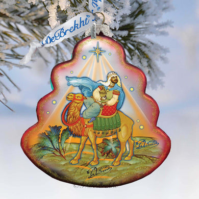 A decorative ornament featuring a man riding a camel, with a star above them, and a snowy background.