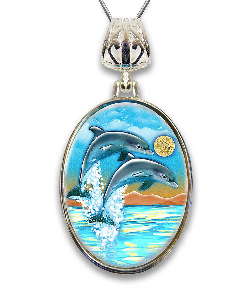 A pendant with a painting of two dolphins leaping out of the water, set against a backdrop of a sunset and ocean.