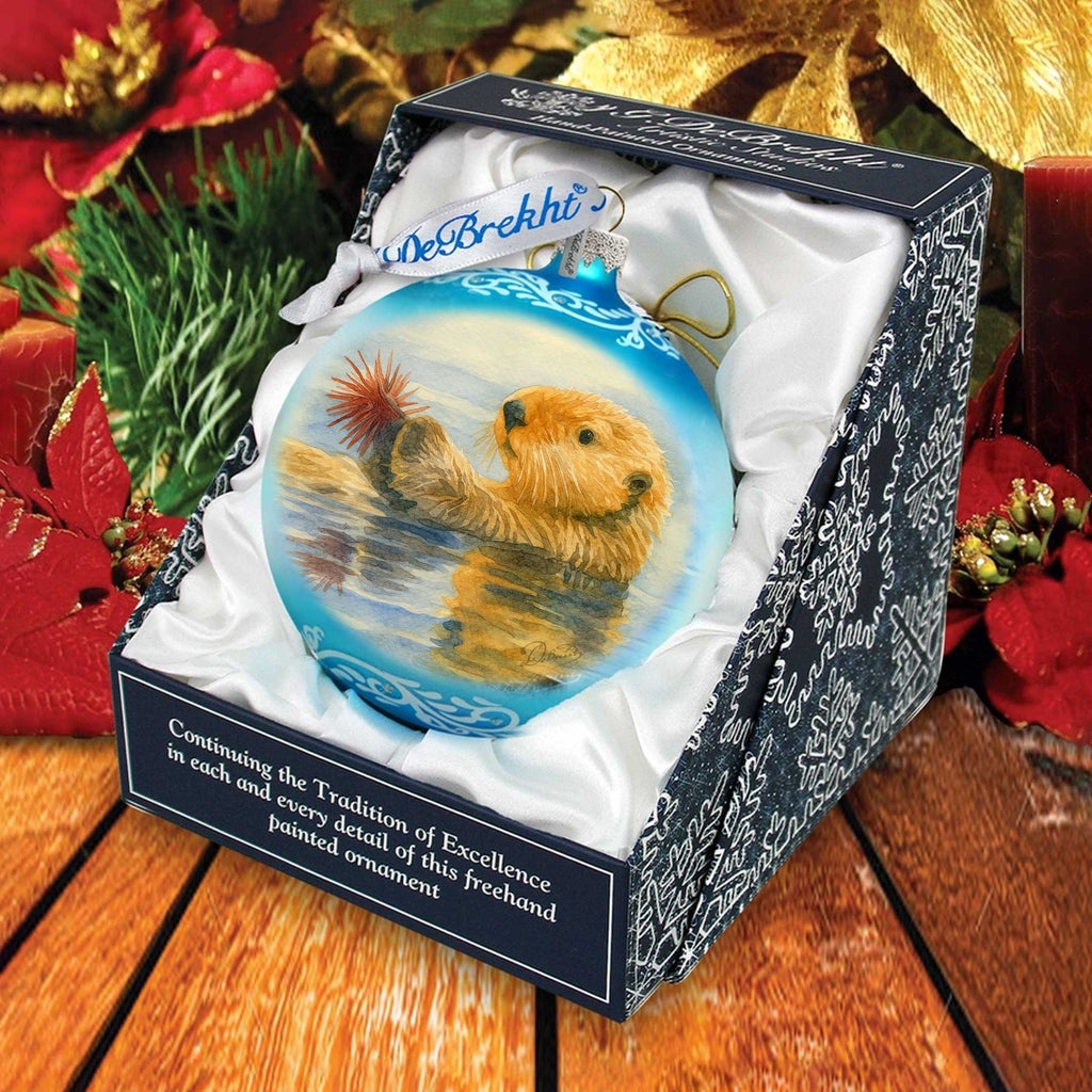 A blue ornament in a box, featuring a picture of a brown bear swimming in a body of water.