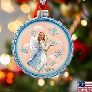 A glass ornament featuring an angel with wings and doves, set against a blurred background with Christmas lights.