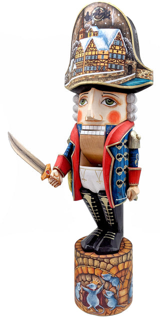 A wooden nutcracker figurine wearing a hat with a detailed scene of a town on it, holding a sword in its hand.