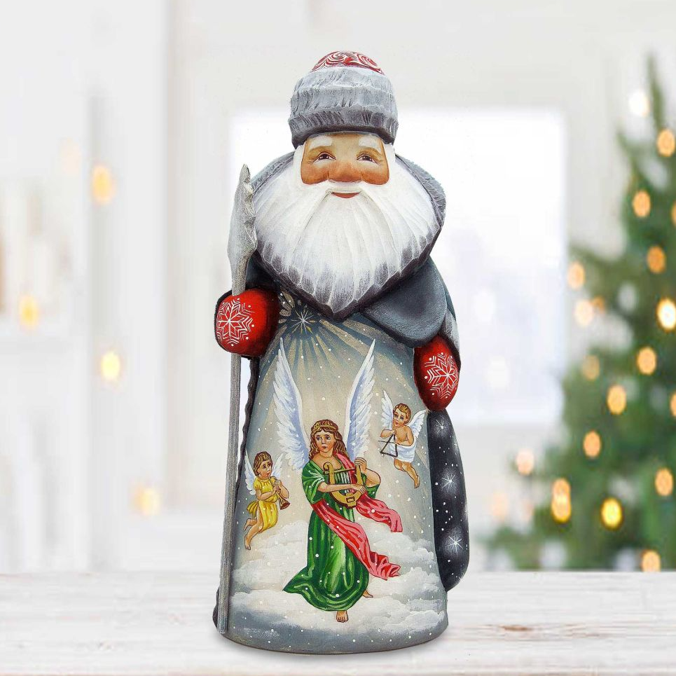 A hand-painted figurine of Santa Claus with angels, set against a blurred background of a Christmas tree.