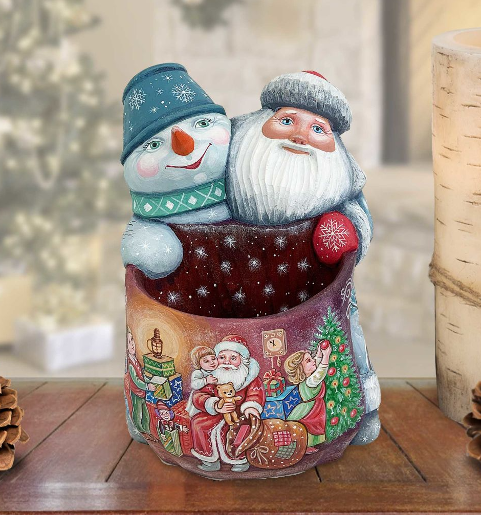 A colorful ceramic Christmas ornament depicting Santa Claus and a snowman, with a tree and presents visible in the background.
