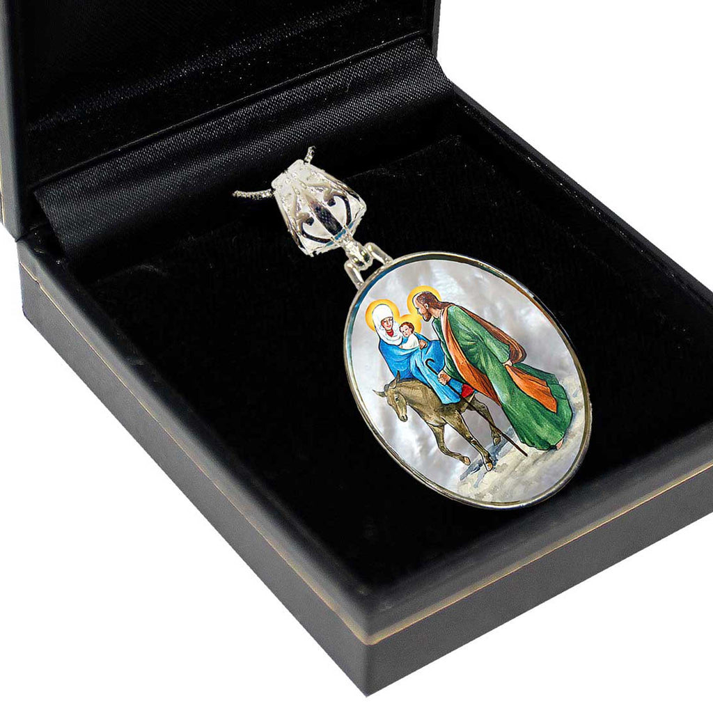 A pendant with a religious scene, featuring a figure of Jesus Christ and a horse, is displayed in a black jewelry box.