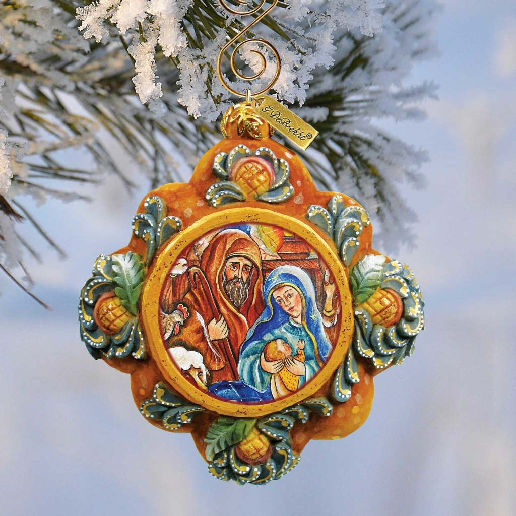 A decorative ornament hanging from a tree branch, featuring a religious scene with a man, a woman, and a baby.