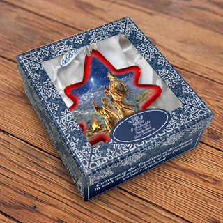 A decorative box with a star-shaped ornament inside, featuring a golden figure against a snowy landscape.