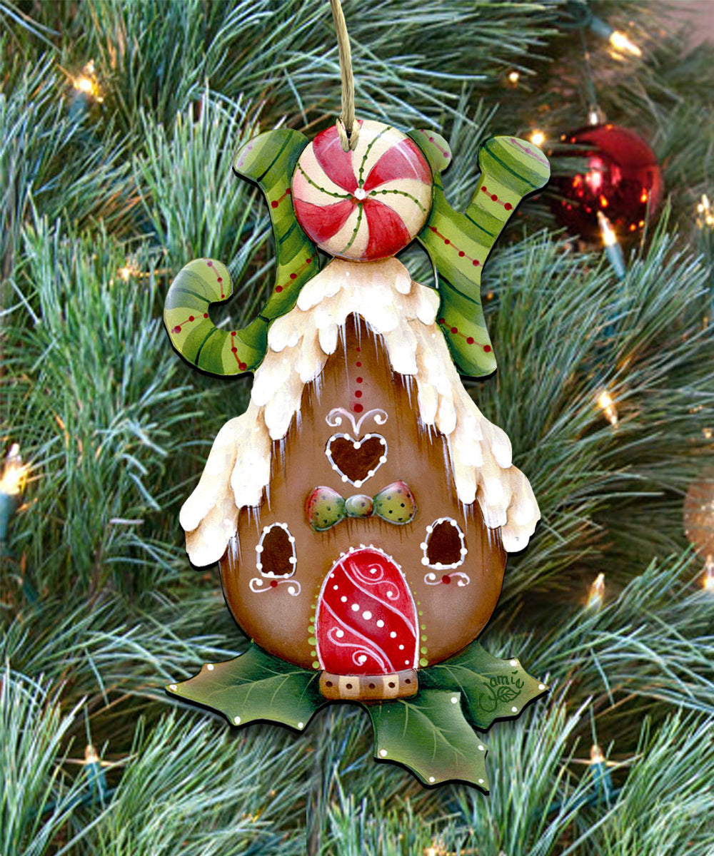 A decorative ornament resembling a gingerbread house, with a candy cane-like design, is hanging on a Christmas tree surrounded by pine needles and twinkling lights.