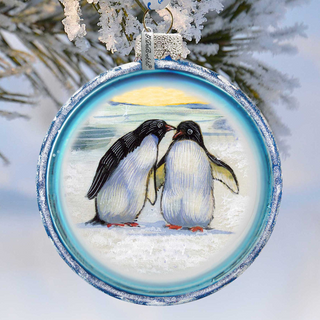 A blue and white ornament featuring two penguins standing together in a snowy landscape.