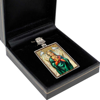 A pendant in a black box, featuring a religious icon with a woman and birds.