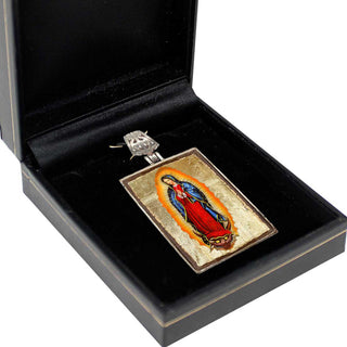 A pendant in the shape of a religious icon, possibly a depiction of the Virgin Mary, is displayed in a black jewelry box.