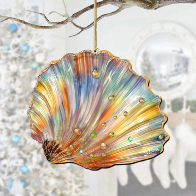 A colorful glass ornament resembling a seashell hangs from a branch, with a blurred background that includes a Christmas tree and a mirror.