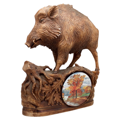 A wooden sculpture depicting a wild boar, with a circular panel below showing a landscape scene.
