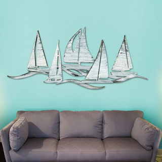 a gray couch against a turquoise wall, with a decorative metal sculpture of sailboats above it.