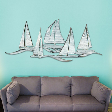a gray couch against a turquoise wall, with a decorative metal sculpture of sailboats above it.