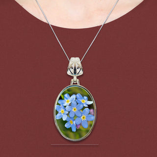 A necklace with a pendant featuring a close-up image of blue forget-me-not flowers.