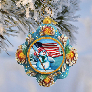 A colorful ornament featuring a snowman, an American flag, and pine cones, hanging from a tree branch.