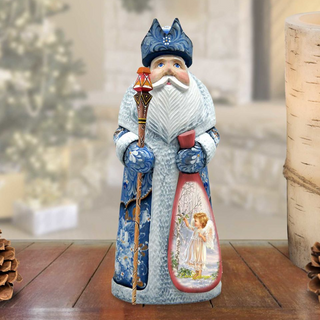 A figurine of Santa Claus holding a bag with an angel image inside, standing on a wooden surface with pine cones in the background.