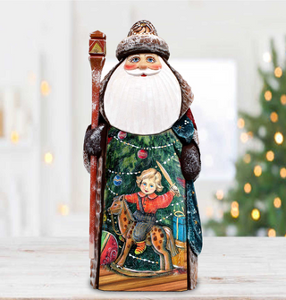 A wooden Santa Claus figurine holding a red staff and a child riding a rocking horse, with a Christmas tree in the background.