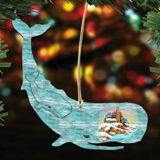A blue whale ornament with a lighthouse and snowy landscape inside, hanging against a blurred background with colorful lights.