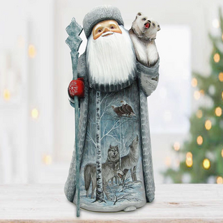 A figurine of Santa Claus holding a reindeer and a bear, with a snowy winter landscape depicted on the front of the Santa Claus figure.