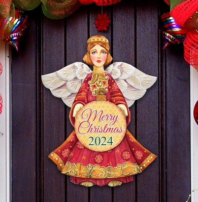 A Christmas-themed paper cutout of an angel holding a sign that says 
